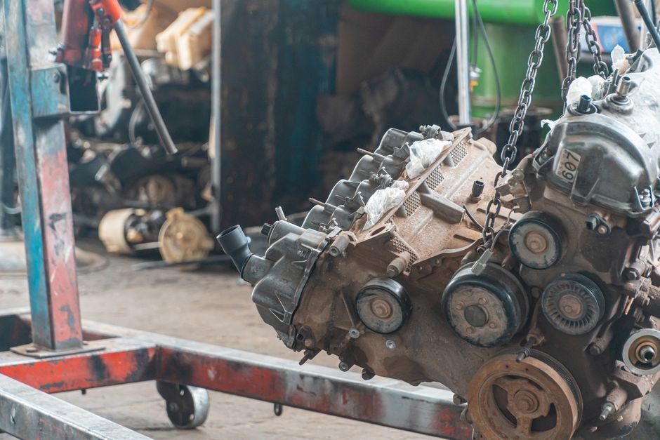 A professional mechanic using a transmission jack to separate the transmission from the engine block